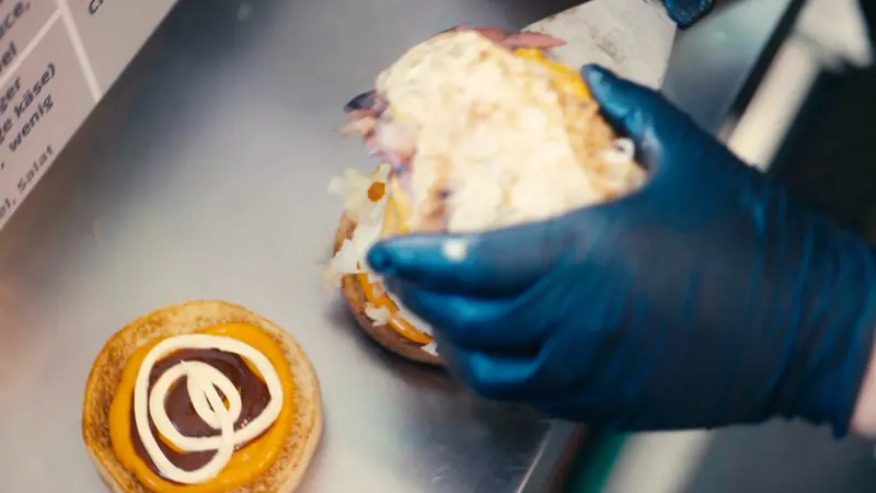 Der Burger wird mit Handschuhen zusammengesetzt
