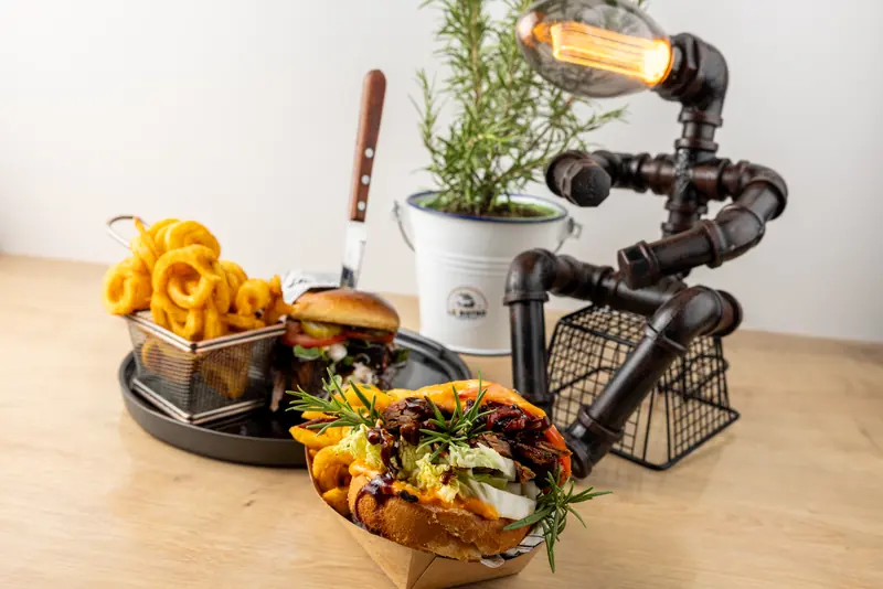 Burger, Curly Fries und eine gefüllte Street-Food-Schale mit Rosmarin und Lampe als Tischdeko