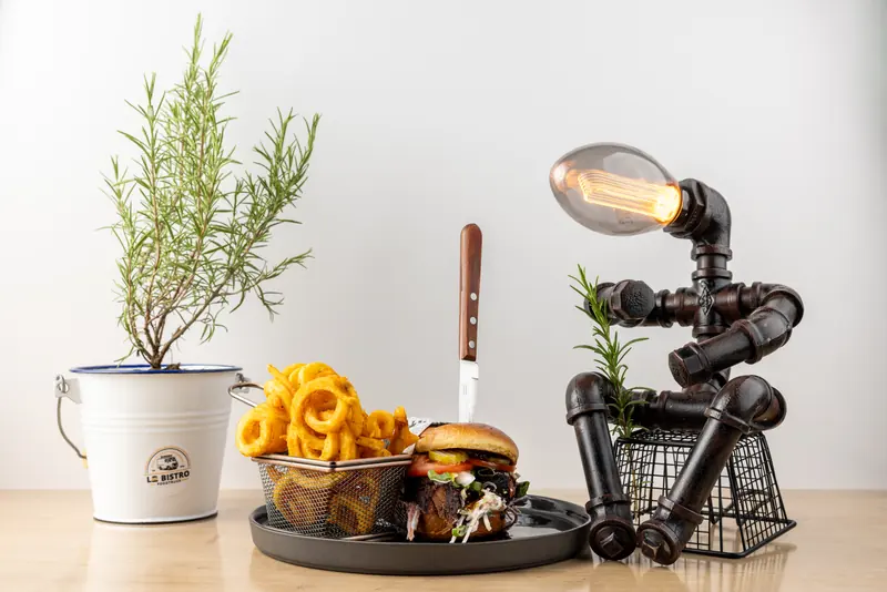 TS1952 Burger mit Curly Fries, dekoriert mit Rosmarin im Le-Bistro-Kübel und einer Industrie-Lampe