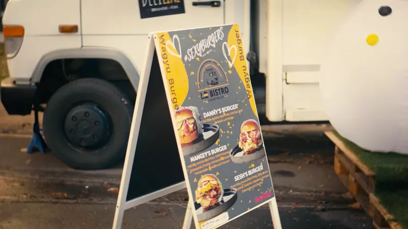 Aufsteller mit Wagyu Burger und der Le-Bistro-Karte neben dem Foodtruck