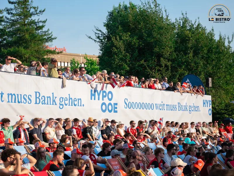 Volle Ränge hinter einem Werbebanner, Public Viewing Sandburg Linz