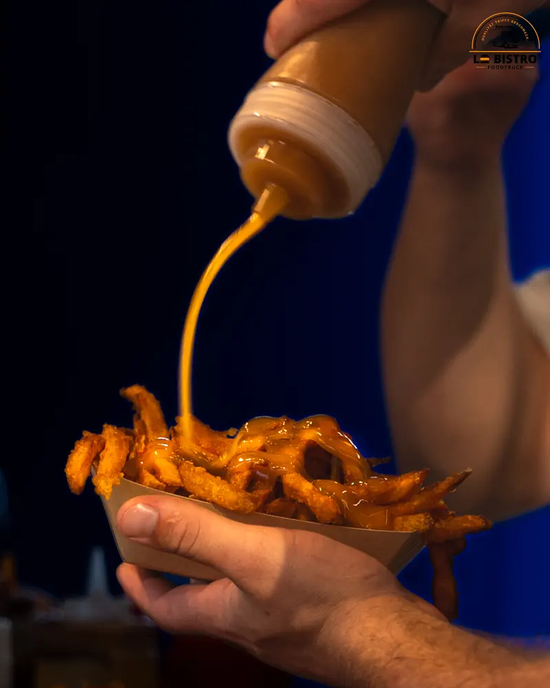 Sauce wird über eine Schale Pommes gegeben, frisch aus dem Truck