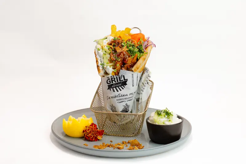 Beef Gyros von Tiligo in der Pita mit gezupftem Rind, Kräutern und Pommes, daneben Tzatziki