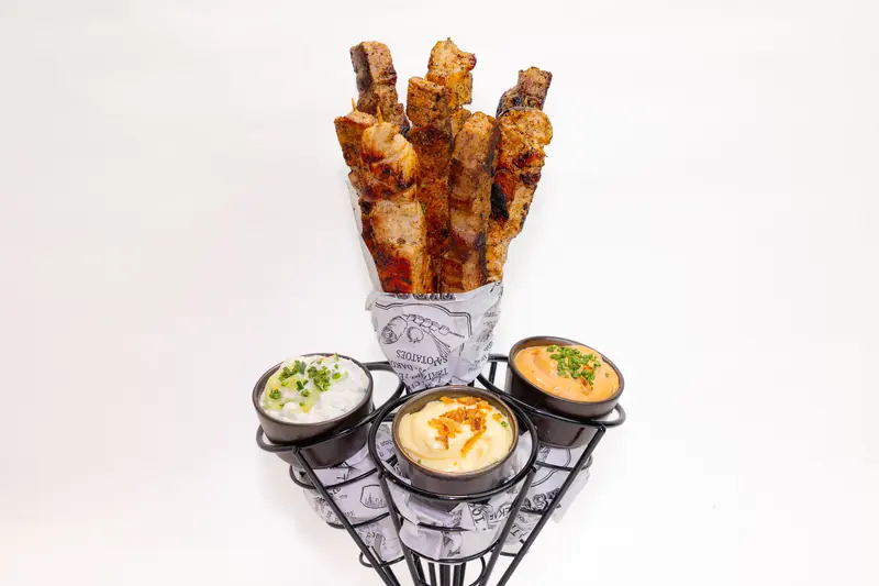 Souvlaki-Spieße von Tiligo im Papier mit drei Dips